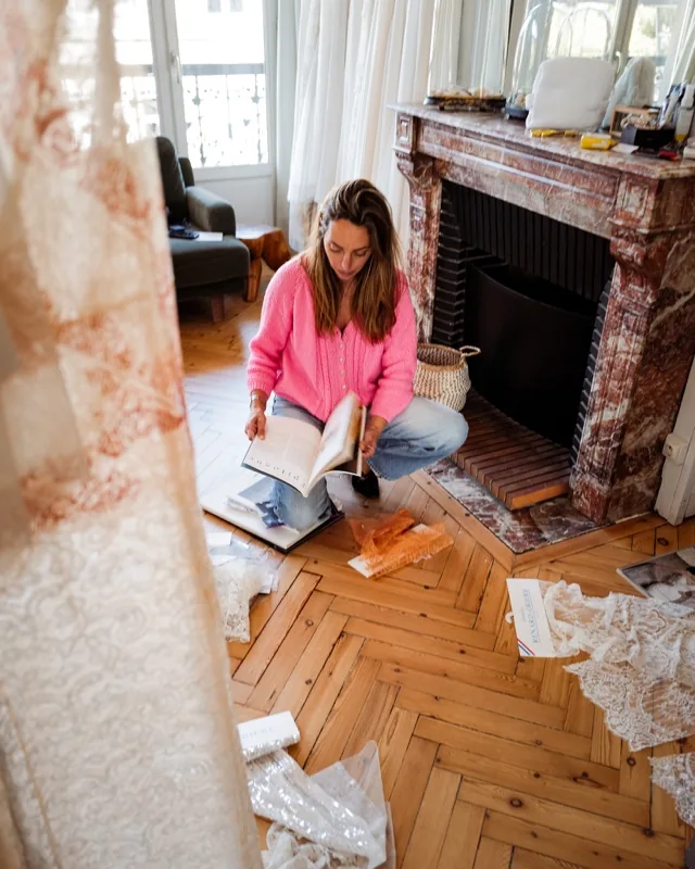 Elsa choisit ses dentelles et ses matières au showroom, échantillons étalés sur le parquet