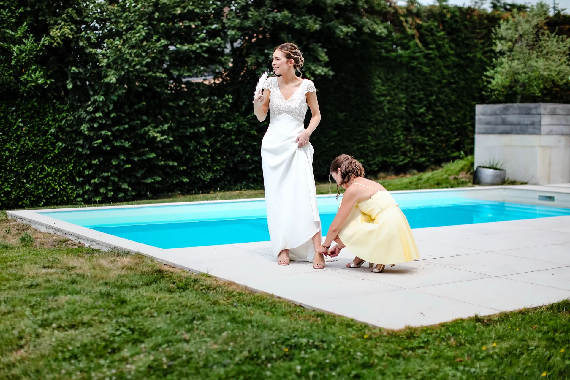 Aurélie au bord de la piscine, une proche ajuste le bas de sa robe