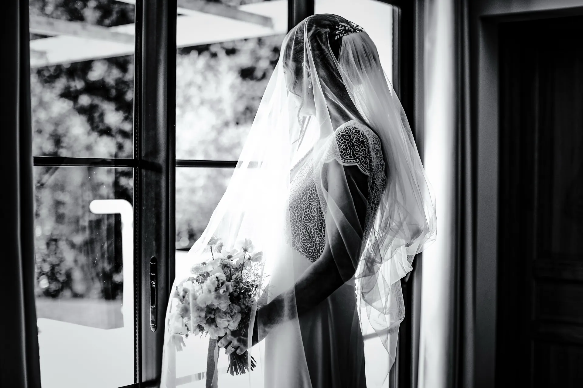 Aurélie sous son voile, silhouette en noir et blanc devant la baie vitrée