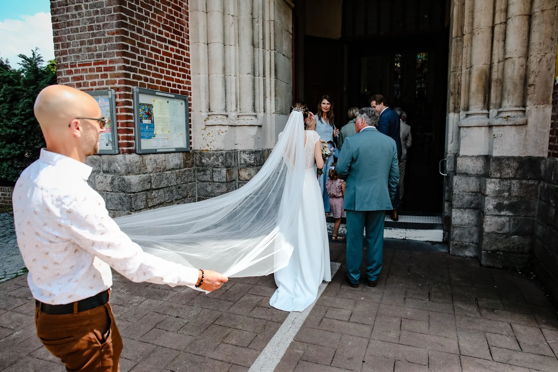 Aurélie arrive à l'église, son long voile déployé derrière elle