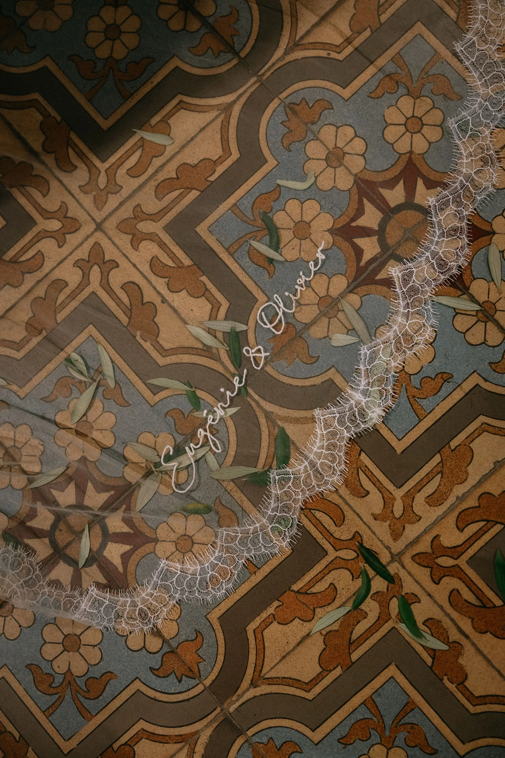 Le voile, bordé de dentelle de Calais et brodé de leurs prénoms, posé sur un carrelage ancien