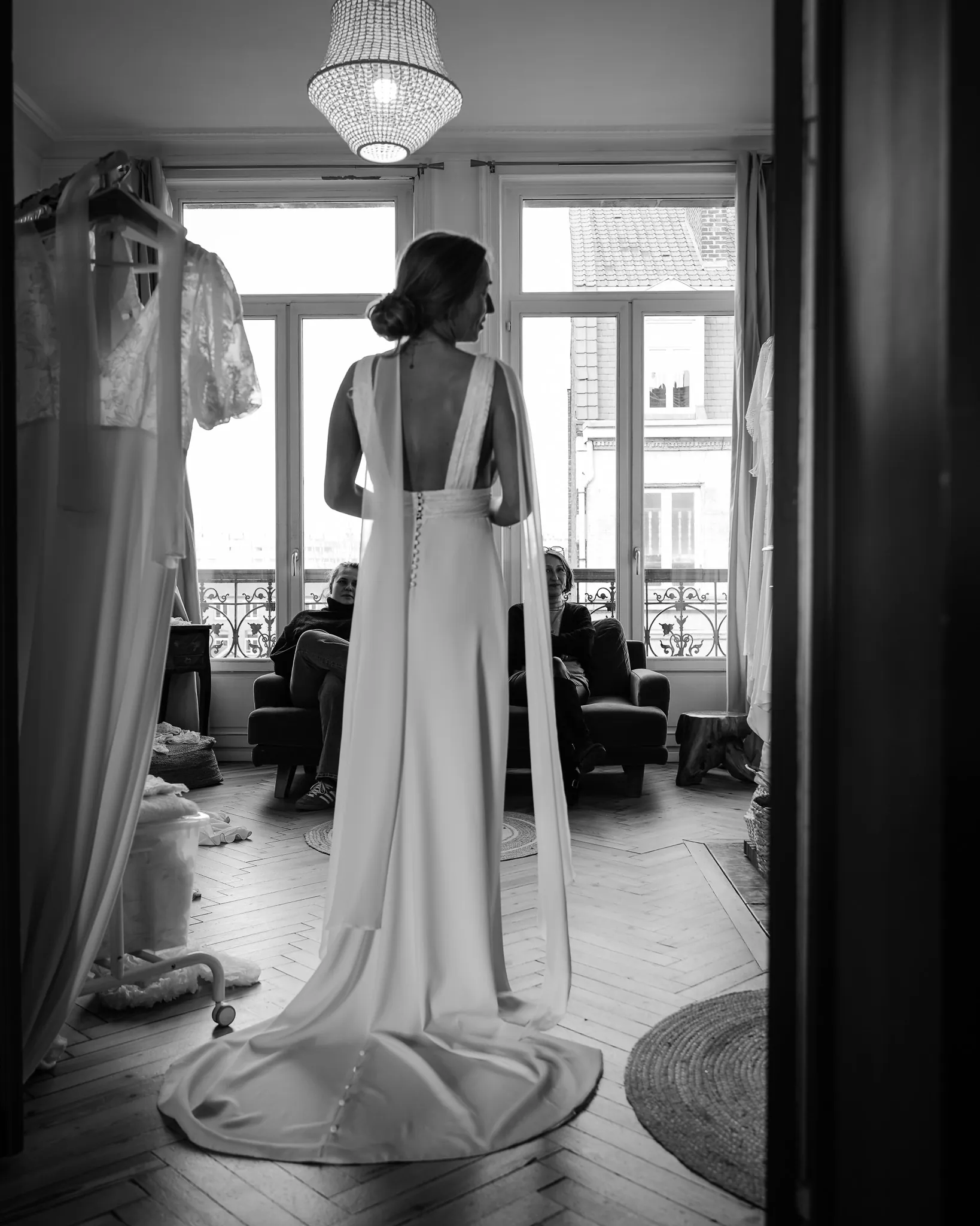 Premier essayage : la robe vue de dos, son dos ouvert, ses bretelles et sa longue traîne, en noir et blanc