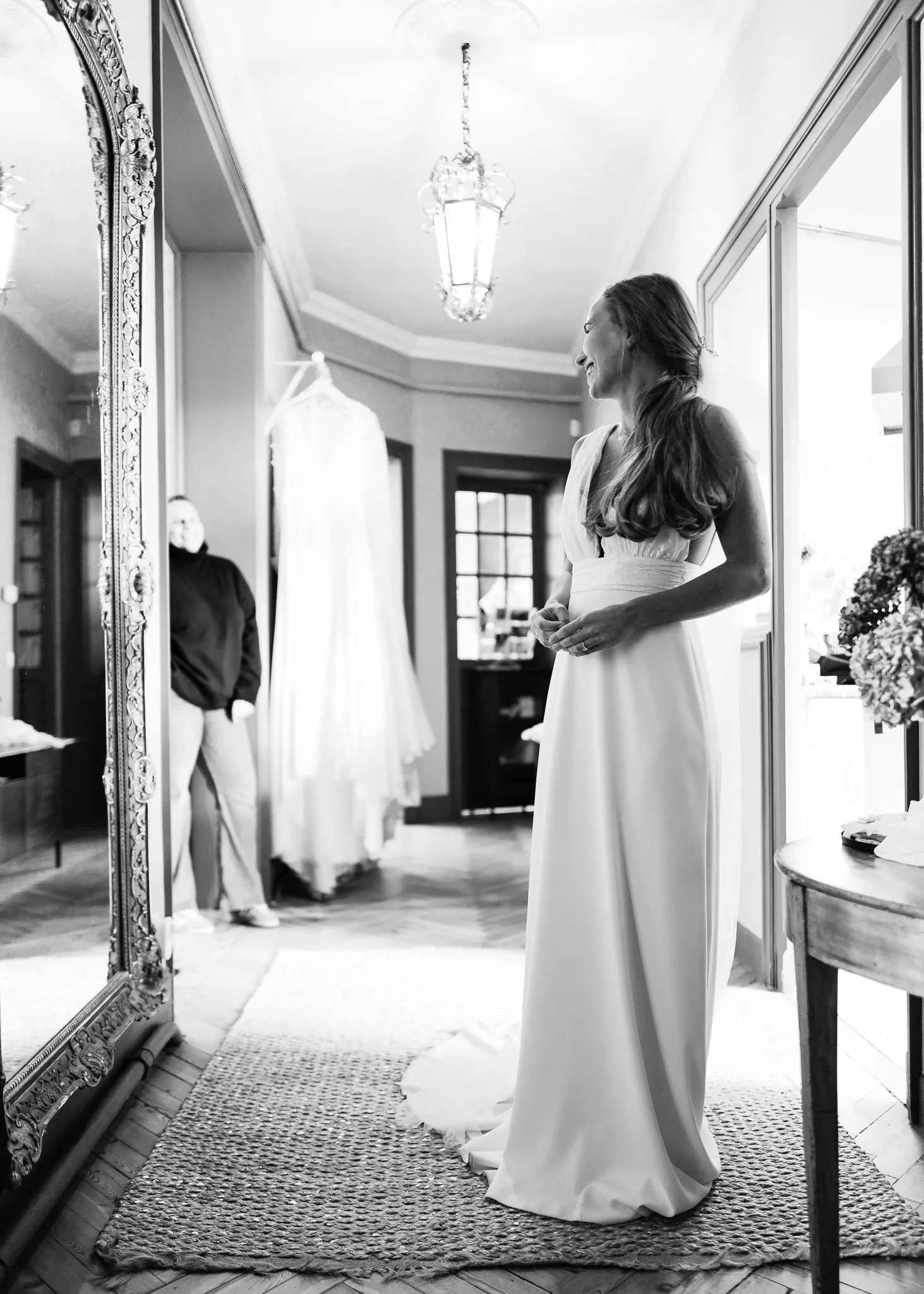 Eugénie dans la robe, de trois quarts devant le grand miroir, en noir et blanc