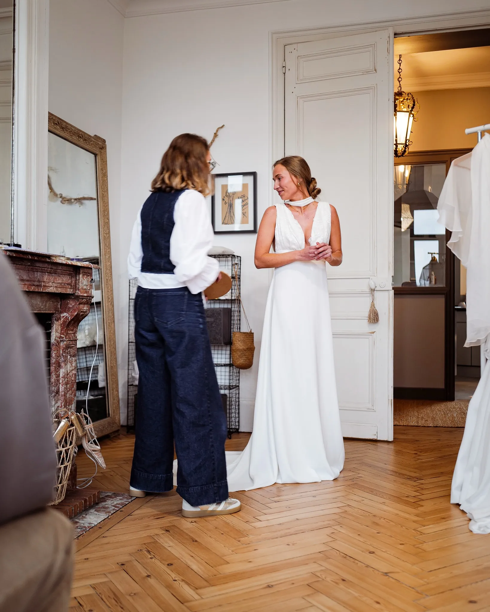 Eugénie dans la robe à décolleté en V et large ceinture, face au miroir du showroom