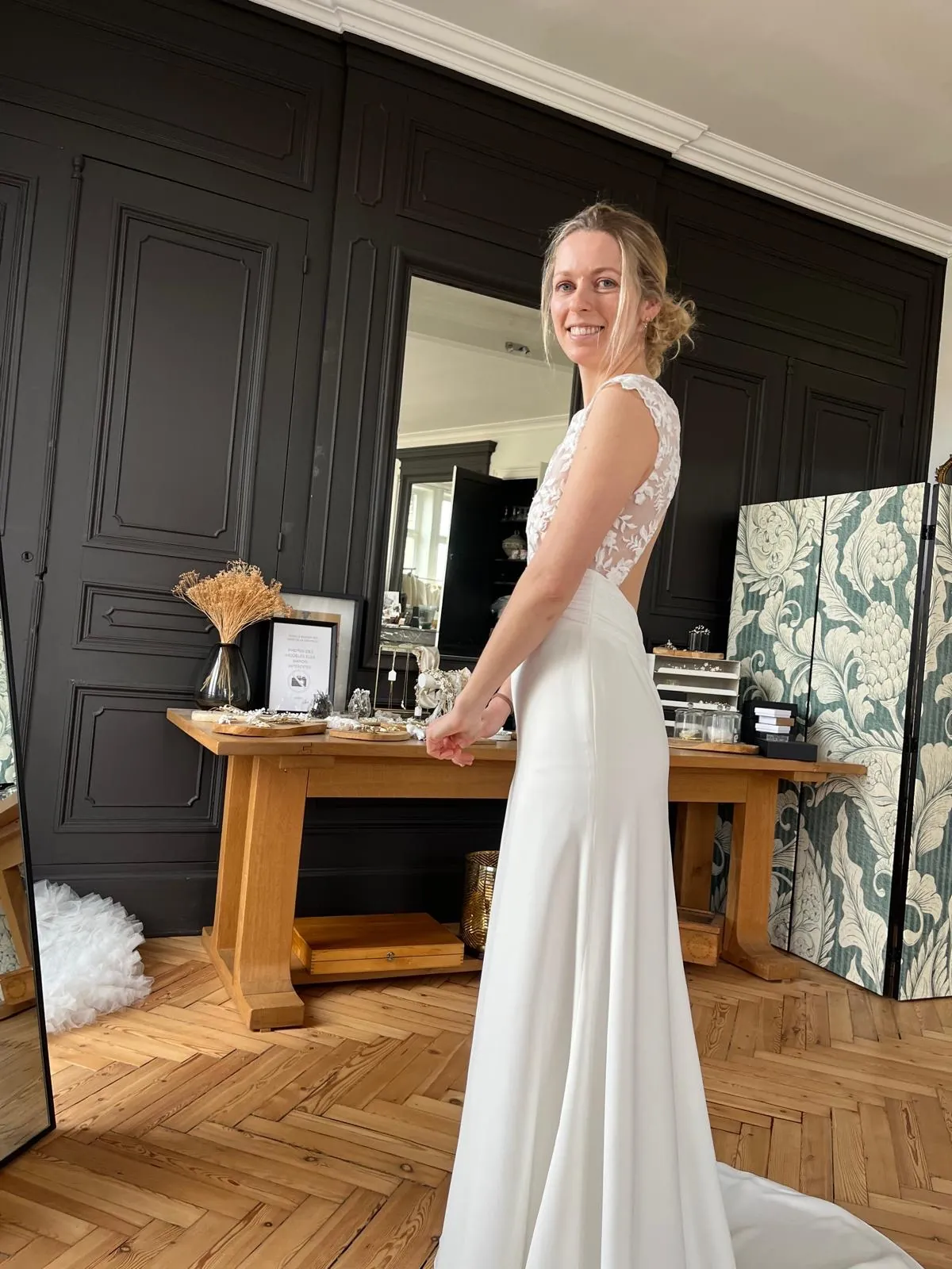 Lola de profil, souriante par-dessus l'épaule : la silhouette sirène de la robe LIYA et son dos échancré