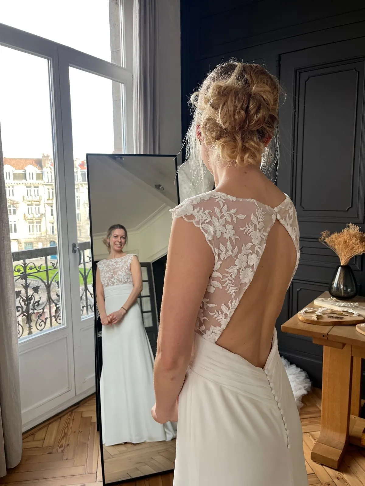Lola de dos devant le miroir : le dos échancré, bordé de tulle brodé, de la robe LIYA