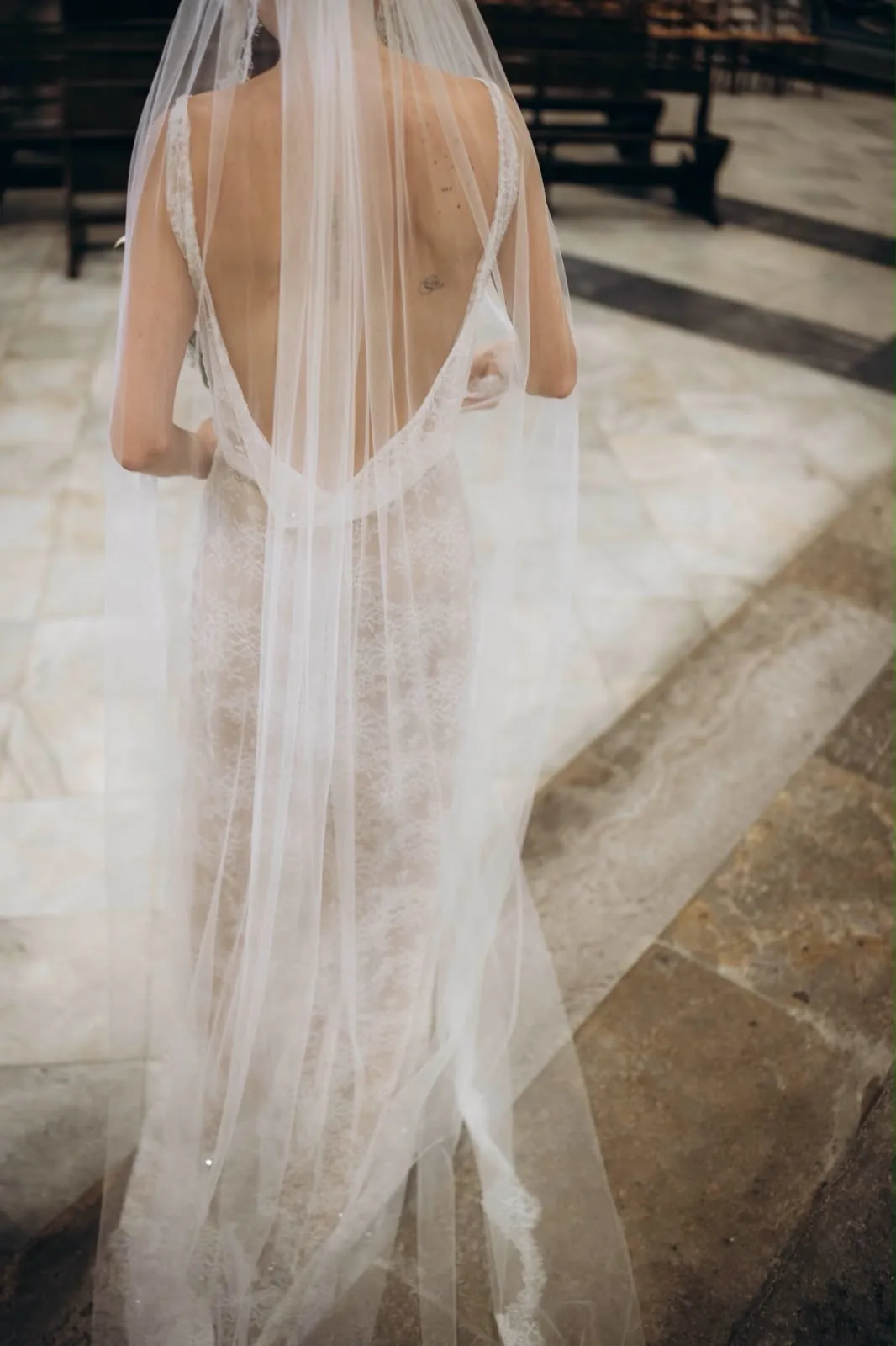 Marie de dos sous son long voile, le dos bénitier de la robe sur un sol de dalles