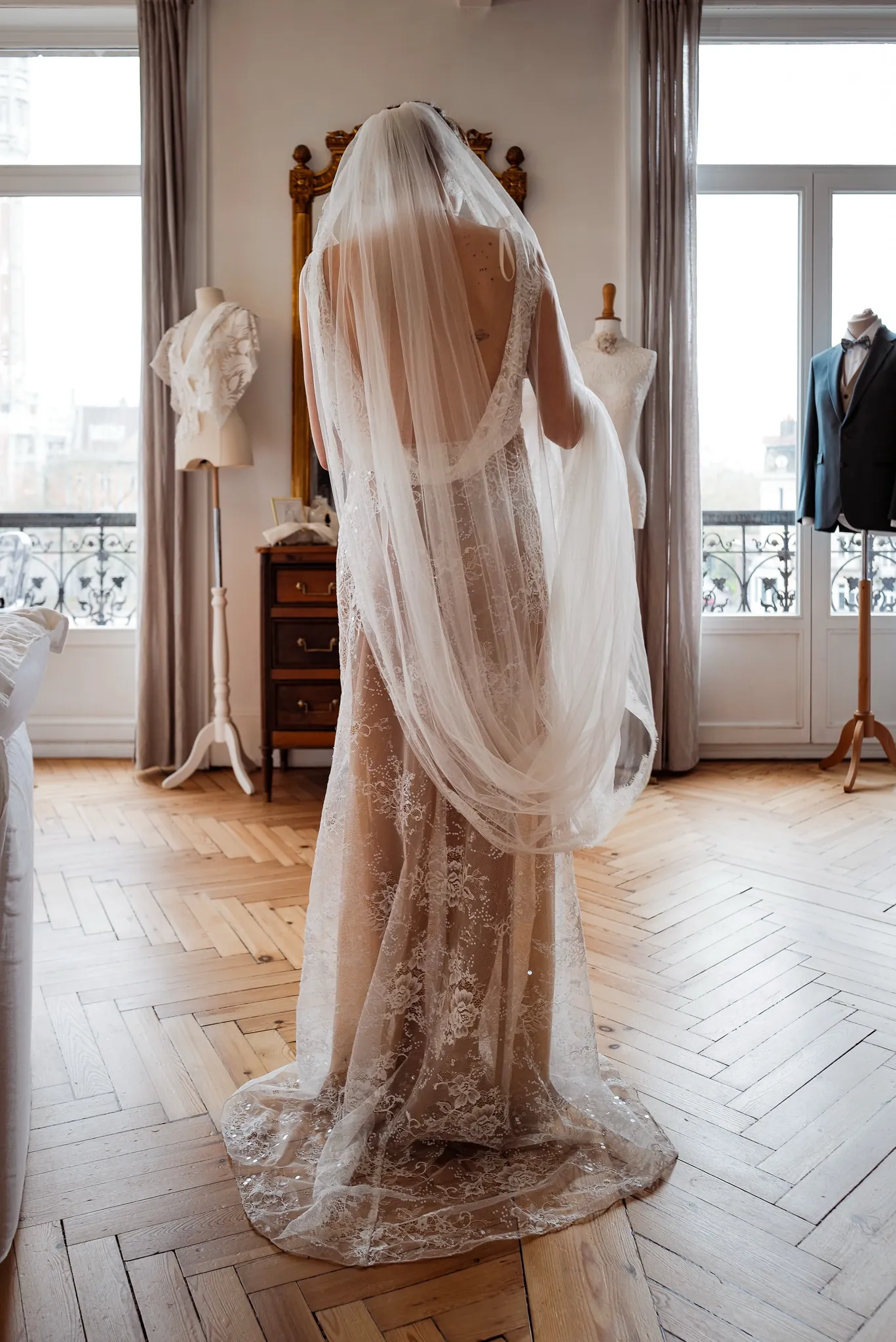 Premier essayage : la robe ALBA tout en dentelle et son long voile, vue de dos, au showroom Elsa Barois