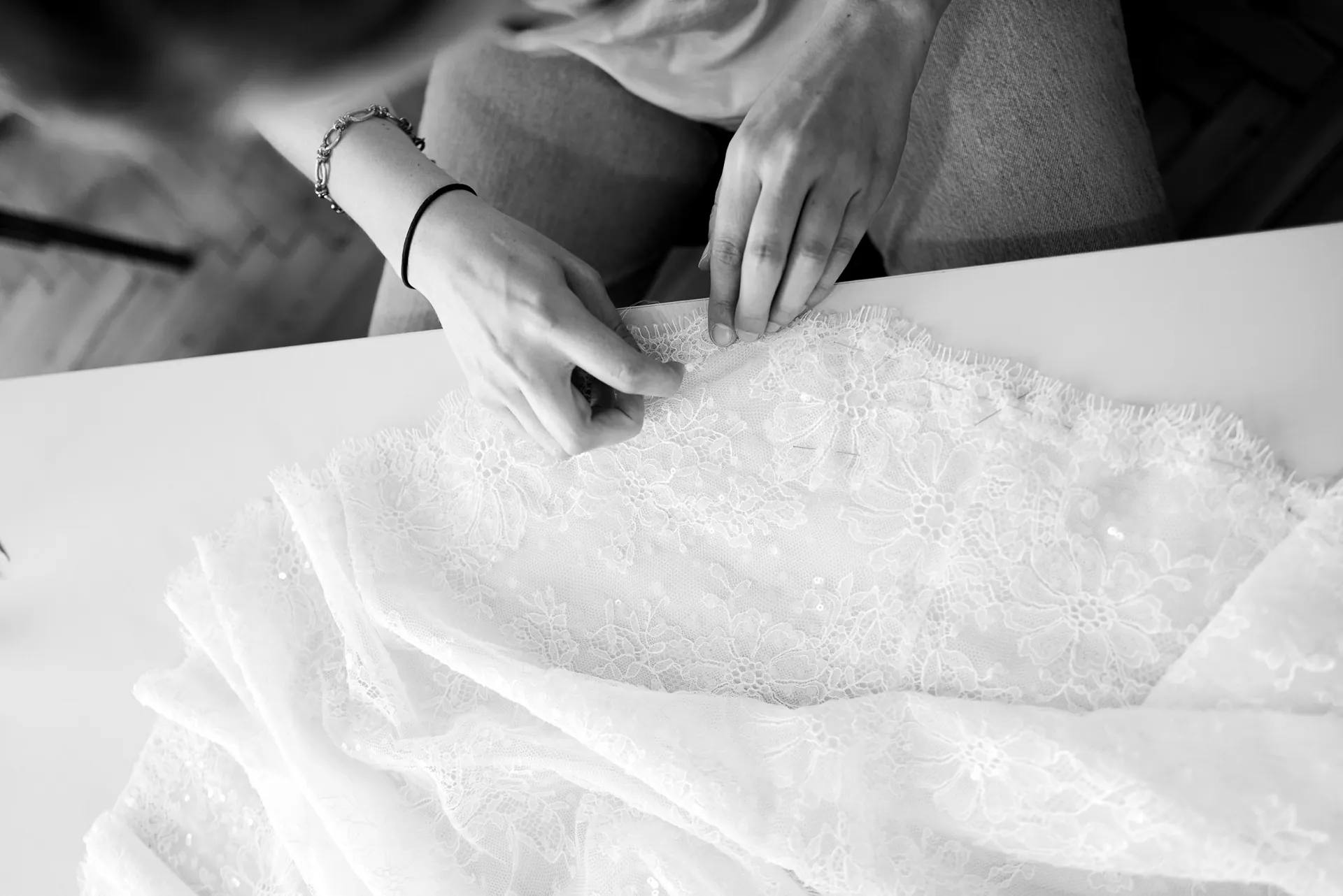 Les mains de la couturière sur la dentelle, en noir et blanc