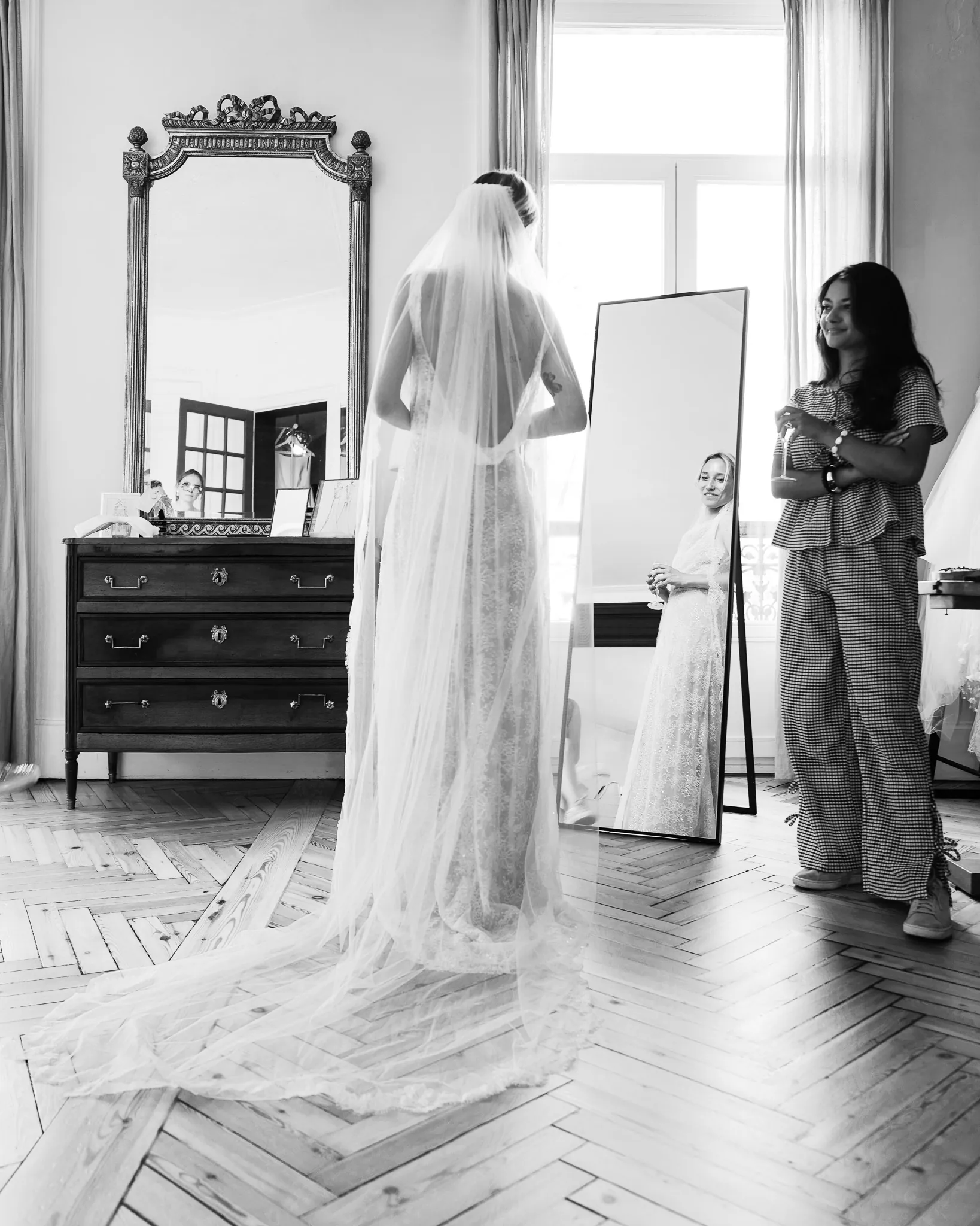 Le long voile déployé sur le parquet, Marie de dos, en noir et blanc